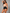 A woman modeling a two-piece shapewear set consisting of a beige strapless bandeau top and black high-waisted briefs with lace trim, set against a textured gray studio background.