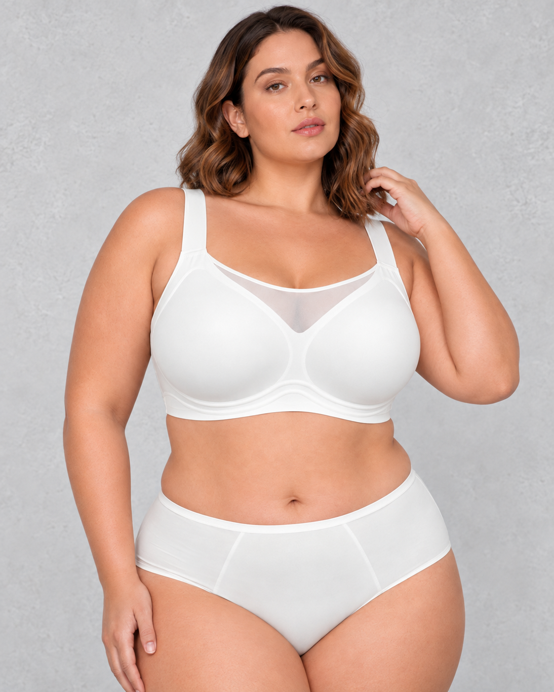 A woman wearing a light beige wireless bralette with a sheer mesh V-neckline detail, paired with light-wash blue jeans.
