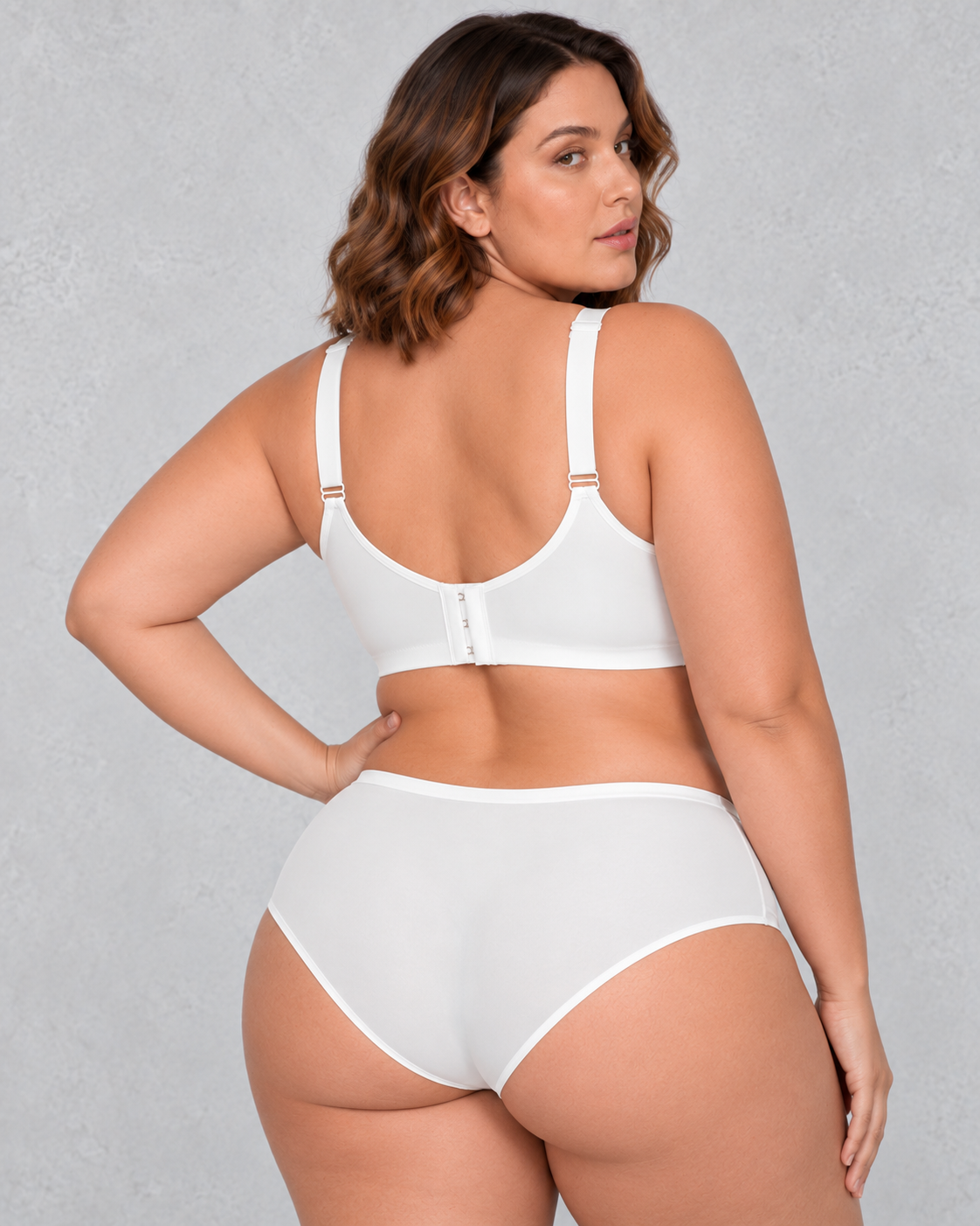 A woman wearing a light beige wireless bralette with a sheer mesh V-neckline detail, paired with light-wash blue jeans.