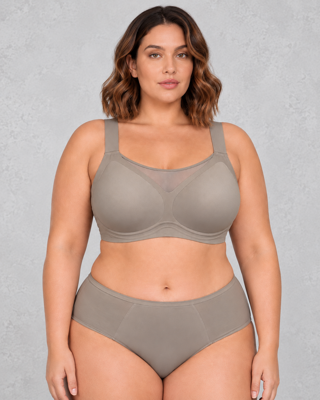 A woman wearing a light beige wireless bralette with a sheer mesh V-neckline detail, paired with light-wash blue jeans.