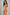 A woman modeling a beige bodysuit and matching high-waisted briefs against a plain gray studio background.