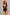 A woman modeling a black one-piece swimsuit with a keyhole cutout at the bust, photographed against a plain light gray studio background.