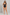 A woman modeling a black one-piece swimsuit with a keyhole cutout at the center, set against a textured gray studio backdrop.