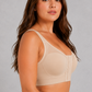 A woman modeling a beige two-piece shapewear set consisting of a bralette and a high-waisted brief, shown against a neutral gray studio background.